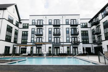 A large white building with black trim and a pool in front.